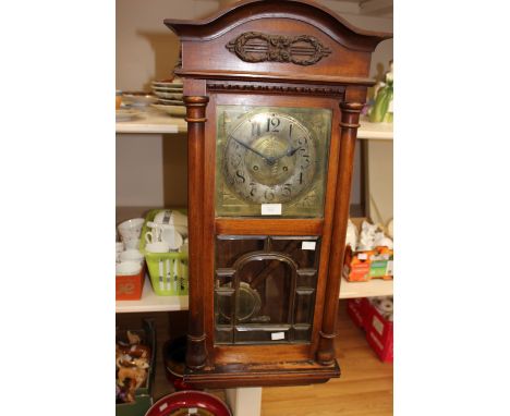 An Art Nouveau walnut cased eight day wall clock, the dial with a silvered chapter ring and brass centre, the door inset with