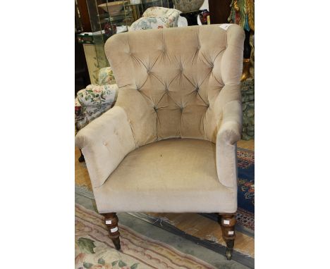 A 19th Century upholstered wing back armchair, deep button backed, cream upholstery raised on raised on turned leg