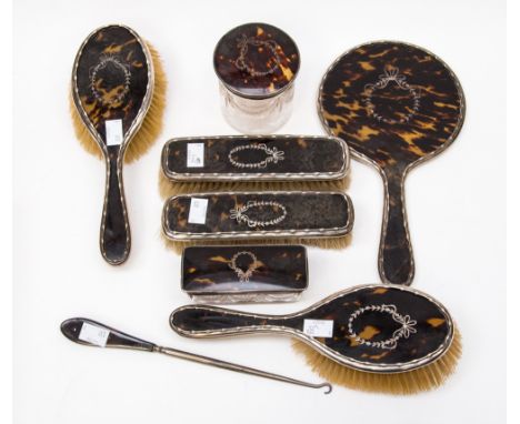  A Tortoiseshell 8 piece dressing table set comprising of 4 brushes,with silver trim/silver handles, a silver handled mirror.