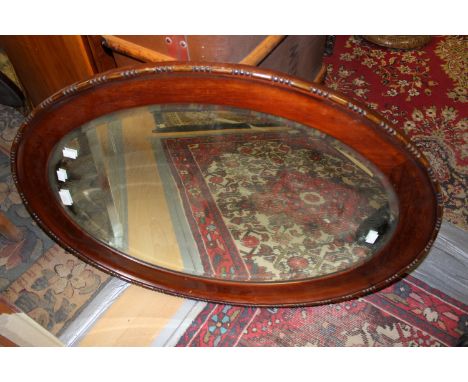 An Edwardian mahogany oval wall mirror, bevelled edge glass