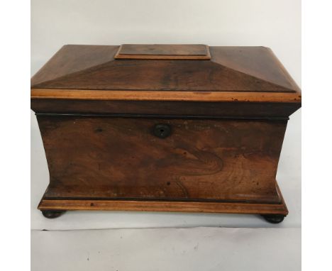 An early 19th century, large mahogany sarcophagus tea caddy with contents raised on squat ball feet  