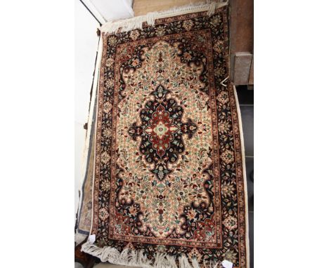 A small hand knotted woollen rug, with a cream ground and blue border, with symmetrical stylised floral patterns,m measuring 