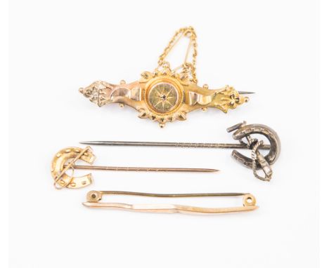 Four items of jewellery comprising a 9ct gold horseshoe stick, a silver stick pin, an Etruscan style 9ct Victorian brooch and