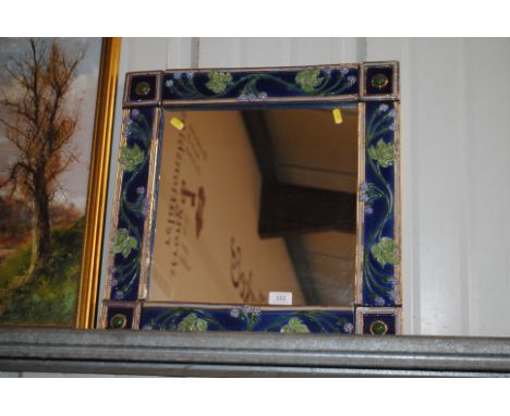 A decorative ceramic framed wall mirror with foliate decoration