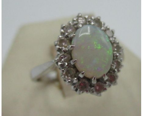 Hallmarked 18ct white gold ring with central oval opal and a halo of twelve round cut diamonds, by PPLD, 750, Birmingham, 198