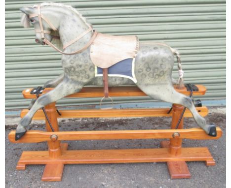 A 20th Century Grey Painted Rocking Horse, with brass-studded leather saddle and under blanket, on a trestle base with turned