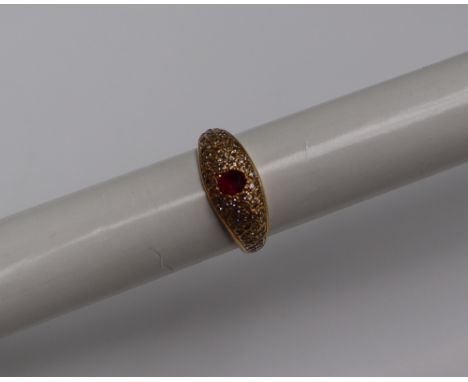 A yellow metal ruby and diamond ring, set with a central oval faceted ruby and numerous round brilliant cut diamonds, size P,