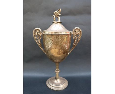 A Victorian silver twin handled trophy cup and cover, the domed cover with a finial in the form of a sailor holding a gun, th