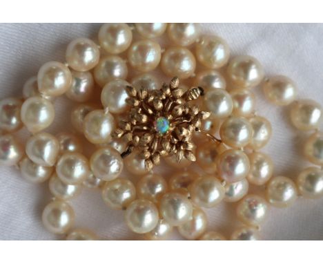 A pearl necklace set with sixty two large regular pearls to a 14ct yellow gold opal set clasp, approximately 64cm long