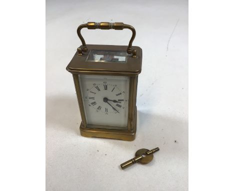 Brass Carriage clock with bevel edge top window, sides and back. Enamel dial with Roman numerals. Complete with original key.