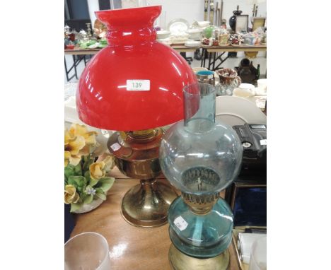 An oil lamp with brass base and two tone red and white glass shade