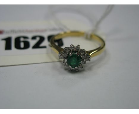 An 18ct Gold Emerald and Diamond Cluster Ring, claw set throughout, between tapered shoulders.