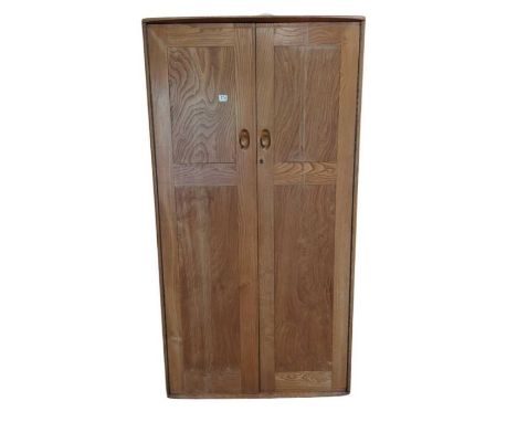 An Ercol double two door wardrobe with hanging rail, supported on roller casters. Manufacturer's label to door, 183cm high, 1