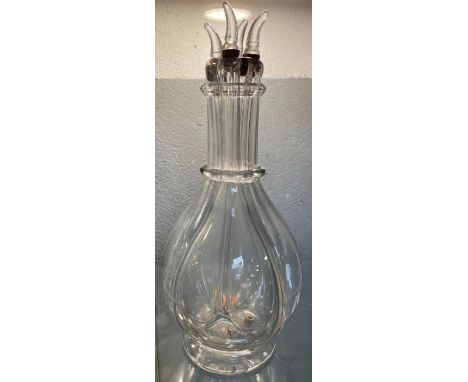 An unusual clear glass four compartment decanter of bottle form and with four small stoppers fitted to the top, 31cms high to