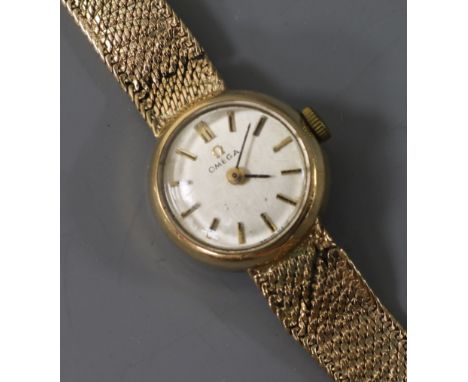 A lady's 9ct gold Omega manual wind wrist watch with an integral 9ct gold bracelet.