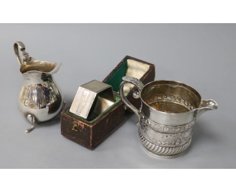A Scottish Victorian silver cream jug, another silver cream jug and a cased napkin ring, the Scottish jug embossed with swags