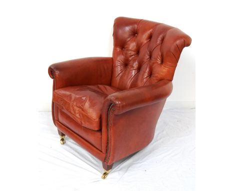 TAN LEATHER BUTTON BACK ARMCHAIRwith scroll arms and decorative metal stud work, standing on stout tapering front supports wi