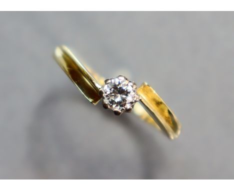 A yellow metal cross-over ring set single diamond; size: P; 2 gm. 