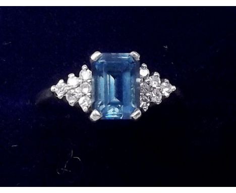 A gold ring set blue topaz flanked by diamonds - size K/L