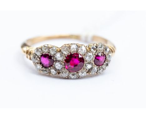 An 18ct gold ruby and diamond ring, comprising three round cut ruby's within diamond set borders, size O, total gross weight 