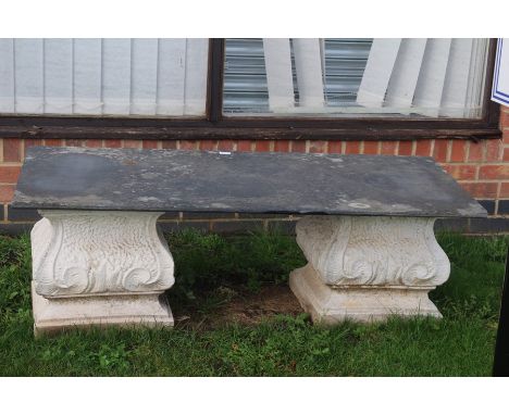 **AWAY** An early 20th century carved stone bench, dark tile top above carved stone plinths.