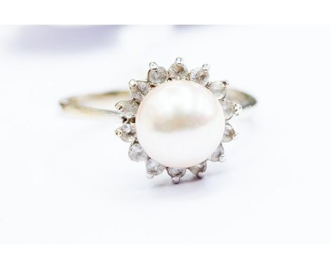 A pearl cluster ring, set with a round cultured pearl, pink tone,&nbsp; size approx. 8mm, with a white stone set border, 18ct