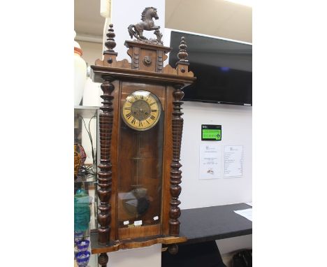 A late 19th Century/early 20th Century walnut Vienna wall clock, prancing horse finial, key and pendulum