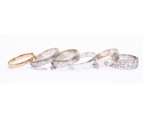 A collection of bangles to include five silver versions, comprising a Victorian style pierced version with foliate decoration