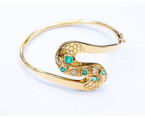 An emerald and diamond bangle,&nbsp; swirl shaped&nbsp; design set with&nbsp; set with emerald cuts and round cut emeralds an