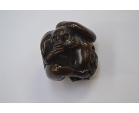 A treen netsuke in the form of a monkey sheltering under a large mushroom, signed 