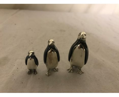 A trio of silver and enamel penguins