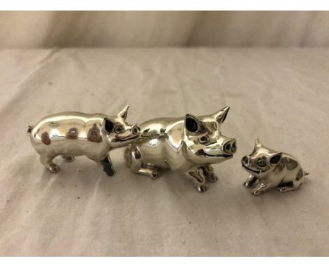 A trio of silver and enamel pigs