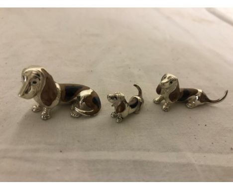 A trio of silver and enamel basset hounds
