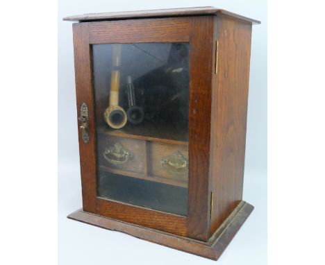 An early 20th century smoker's cabinet, the single glazed door opening to reveal a fitted interior with central arcaded shelf