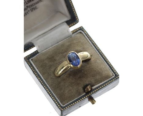 High carat yellow gold backed sapphire single stone ring, rub-over set with an oval sapphire, 1.25ct approx, width 10mm, 7.6g