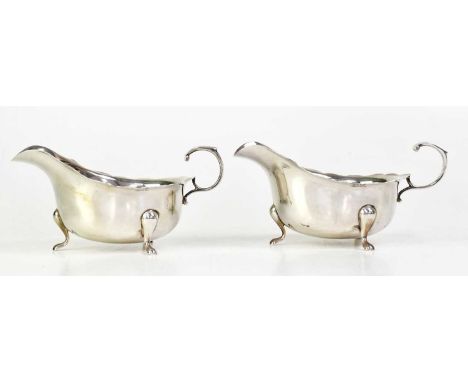 ADIE BROTHERS LTD; a pair of George VI hallmarked silver sauce boats with serpentine edge, flying scroll handles and on three