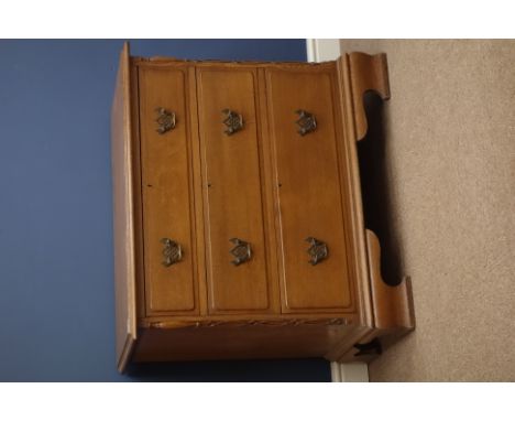 Early 20th century oak chest, three oak lined drawers, applied strap work and half turnings to canted corners, ogee bracket f
