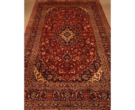 Persian Kashan red ground rug carpet,trailing stylised floral design, dark blue ground pole medallion, stylised flower head b