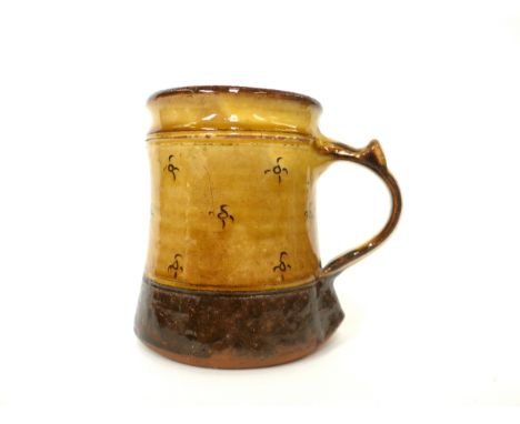 A Winchcombe Pottery Tankard with ochre glaze and incised motif decoration. Impressed pottery seals only. 12.5cm highGlaze lo