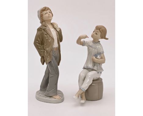 A Lladro figurine of a girl with doll and a Nao figurine of a boy with rucksack