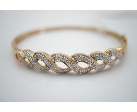 A 9ct gold and diamond hinged bangle, the face of an interlaced design, pellet set with brilliant-cut diamonds, 9.5g