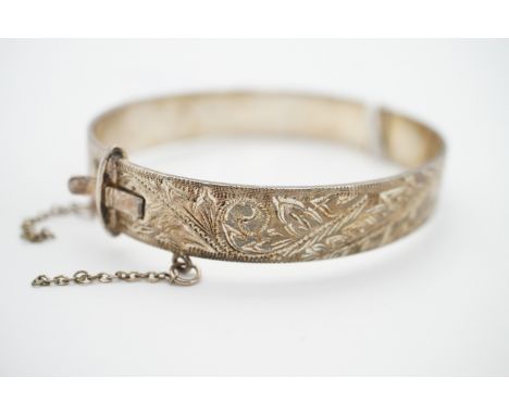 A white-metal hinged bangle, the face having wriggle and bright-cut foliage, 31.8g
