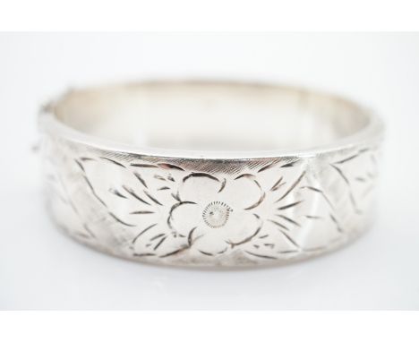A vintage silver hinged bangle, the face decorated with bright-cut primroses, 28.2g