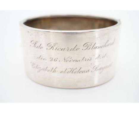 A Victorian white-metal hinged bangle with engraved dedication, the face having foliate engraved decoration, 34.1g