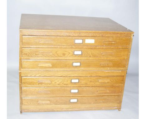 A mid-20thC light oak plan chest, with six drawers centred by name plaques on a block base, 93cm high, 113cm wide, 84cm deep.