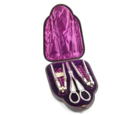 An Edwardian silver plated cased nutcracker and grape scissor set, comprising of two articulated nut crackers, 15cm high, and