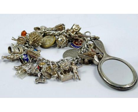 A mid 20thC charm bracelet, with approx 30 silver and white metal charms
