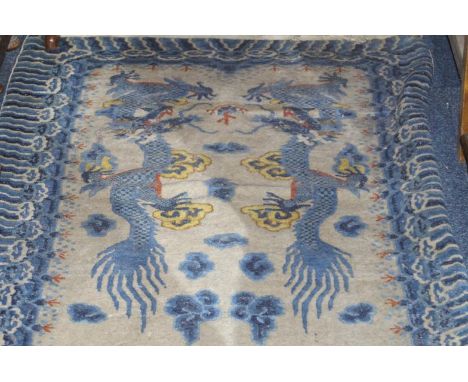 An early 20thC Chinese hand knotted carpet runner, decorated with dragons predominately in blue and yellow in a cream ground 