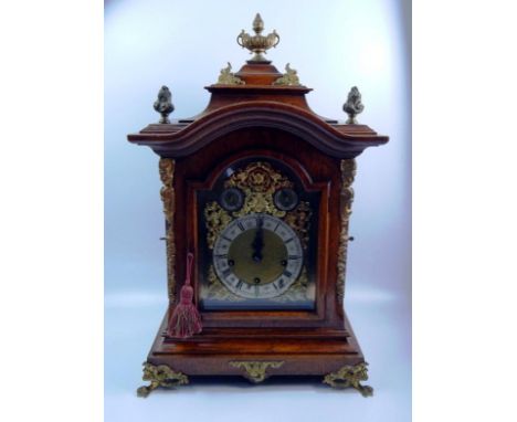A late 19thC/early 20thC oak mantel clock, with gilt metal mounts, the arched dial with elaborate rococo style spandrels, sil