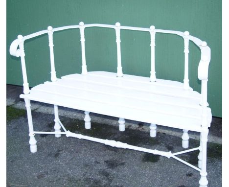 A cast iron and wooden slatted bench, of D-end outline, the scroll top rail raised on bell flower supports with a slatted sea